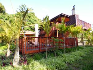 Monzi Safari Lodge في سانت لوسيا: منزل به سطح خشبي وأشجار نخيل