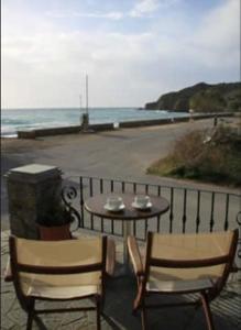 two chairs and a table on a balcony with the ocean at Aigiali Rooms in Volissos