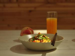 a bowl of food next to a glass of orange juice at Zen Box House in Yangshuo