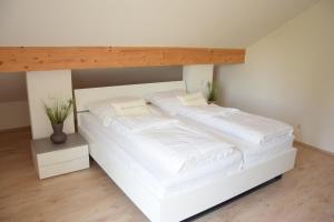 2 łóżka w pokoju z białą pościelą i poduszkami w obiekcie Ferienwohnung Leni w mieście Bad Birnbach