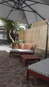 two benches sitting under an umbrella on a patio at Il Melograno in Rimini