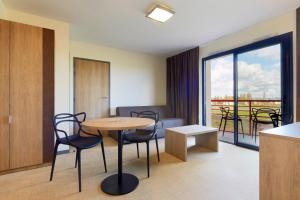 a room with a table and chairs and a balcony at Kyriad Prestige Residence & Spa Cabourg-Dives-sur-Mer in Dives-sur-Mer