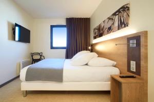 a hotel room with a bed and a tv at Kyriad Prestige Residence & Spa Cabourg-Dives-sur-Mer in Dives-sur-Mer