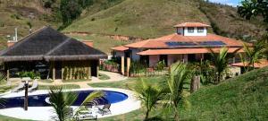 a house with a swimming pool next to a mountain at Hotel Fazenda Cheiro Verde in Mercês