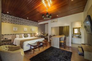 a hotel room with a bed and a dining room at Pousada de Charme Villa do Comendador in Pirenópolis