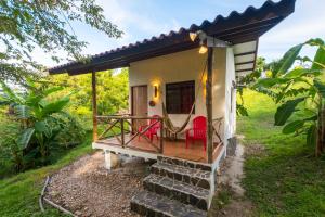 a tiny house with a porch and a red chair at Istmo Beach and Jungle Bungalows in San Carlos