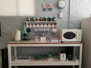 a kitchen with a microwave and a table with dishes at Voni's Cottage in Vredendal +9 photos