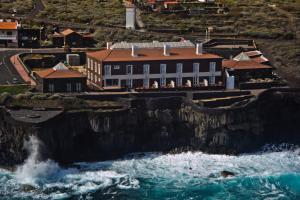 a building on a cliff next to the ocean at Balneario Pozo de la Salud in Sabinosa