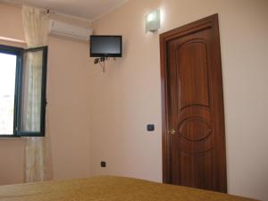 una camera con porta in legno e televisore a parete di Locanda Adele a Parghelia