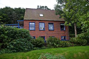 a red brick house with blue windows in a yard at Casa Mundo Bed & Breakfast in Vejle