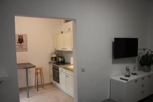 a kitchen with white cabinets and a tv on the wall at Ferienwohnung Bonita in Freital