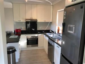 a kitchen with a stainless steel refrigerator and white cabinets at Whale Rock Gardens in Plettenberg Bay