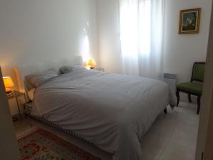 a bedroom with a white bed and a chair at Boléro in Carqueiranne