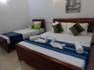 two beds in a room with towels on them at Pick & Go White House in Negombo