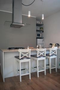 una cocina con 2 taburetes blancos y una barra en Lucky's Home en Enna