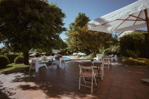 un patio con mesas, sillas y una sombrilla en Casa do Almocreve en Baião