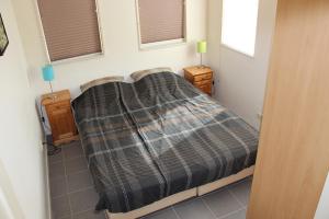 een slaapkamer met een bed met een geruite deken erop bij TS37 in West-Terschelling