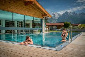 a man and a woman sitting in a swimming pool at Hotel Kitzspitz in Sankt Jakob in Haus