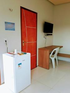 a room with a refrigerator and a desk and a red door at Torre do Sol Park Hotel in Chapadinha