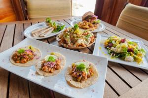 a table with four plates of food on it at Magnific Rock - Surf Resort & Yoga Retreat Nicaragua in Popoyo