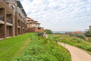 a walkway next to a building with the ocean in the background at Zimbali Suite 104 in Ballito