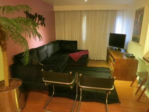 sala de estar con sofá negro y TV en AL - Apto fino, aconchegante e informal, en São Paulo