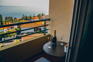 a balcony with a table and two wine glasses at Horizon View Madeira in Caniço