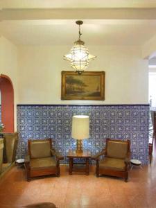 sala de estar con 2 sillas, mesa y lámpara en Hotel Sierra de Alica en Tepic