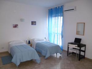 B&B Le Grand Bleu Siracusa - One Hundred Steps From Ortigia -Sea View - في سيراكوزا: غرفة بسريرين ومكتب ولاب توب