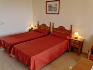 2 posti letto in camera d'albergo con lenzuola rosse di Parque Carolina a Costa Del Silencio