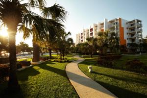 ein Gehweg in einem Park mit Palmen und einem Gebäude in der Unterkunft Royal Decameron Salinitas - All Inclusive in Los Cóbanos