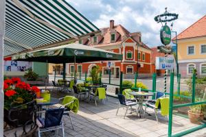 eine Terrasse mit Tischen und Stühlen und einem grünen Sonnenschirm in der Unterkunft Landhotel Groggerhof in Obdach