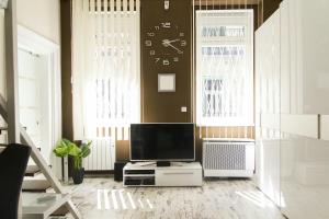 a living room with a tv and a clock on the wall at R&R Apartment Dembinszky in Budapest