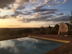 a person sitting on a chair next to a swimming pool at Fonte Cicerum Authentic Villa - a Fontanaro Property in Paciano