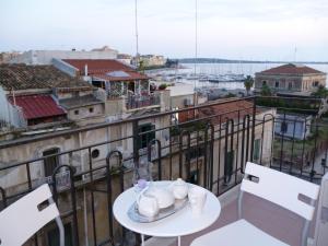 una mesa y sillas en un balcón con vistas en B&B Le Grand Bleu Siracusa - One Hundred Steps From Ortigia -Sea View -, en Siracusa