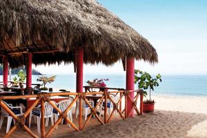 um restaurante com um guarda-sol de palha na praia em Decameron Los Cocos Guayabitos, Ramada All-Inclusive Resort em Rincon de Guayabitos