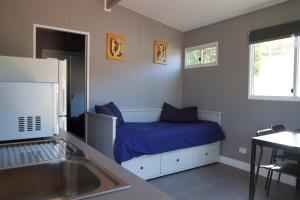 Schlafzimmer mit einem Bett mit blauer Bettwäsche und einem Waschbecken in der Unterkunft Yandina Caravan Park in Yandina