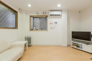 a living room with a couch and a flat screen tv at Awaza House 1 in Osaka