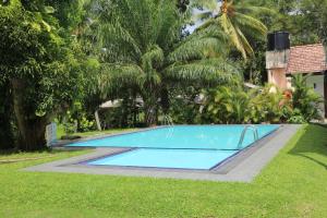 a large blue swimming pool in a yard with trees at Aarya hotel in Pinnawala