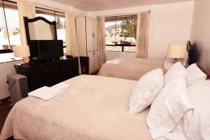 a bedroom with two beds and a mirror and a television at Cusco Retreat in Cusco
