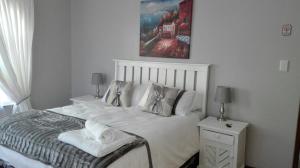 een slaapkamer met een wit bed en een schilderij aan de muur bij Versailles B and B in Gonubie +30 foto's