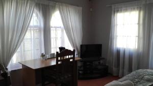 een slaapkamer met een bureau, 2 ramen en een bed bij Versailles B and B in Gonubie