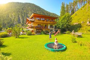 Ein Mann und ein Mädchen spielen auf einem Trampolin vor einem Haus in der Unterkunft ZIRBENNEST Haus Martha in Biberwier