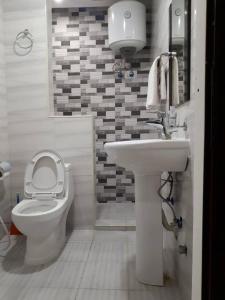 a white bathroom with a toilet and a sink at تاج الخليج للشقق المخدومة in Dammam