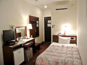 um quarto de hotel com um quarto com uma cama e uma secretária em Leo Plaza Hotel em Sasebo