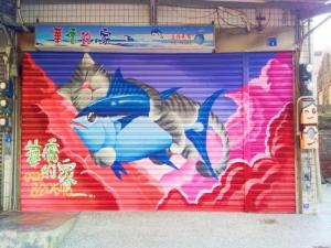una porta del garage con sopra un dipinto di un pesce di Hua Qiao De Jia a Donggang