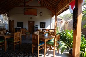 Un comedor con mesas y sillas de madera. en Paradesa Living, en Gili Trawangan