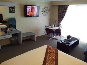 um quarto de hotel com uma cama e uma sala de jantar em Admiral Nelson Motor Inn em Nelson Bay