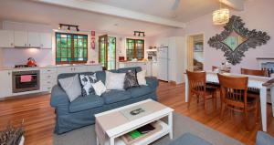 a living room with a blue couch and a kitchen at Crystal Creek Meadows in Kangaroo Valley