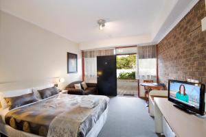 a hotel room with a bed, tv and a desk at Lorne Coachman Inn in Lorne